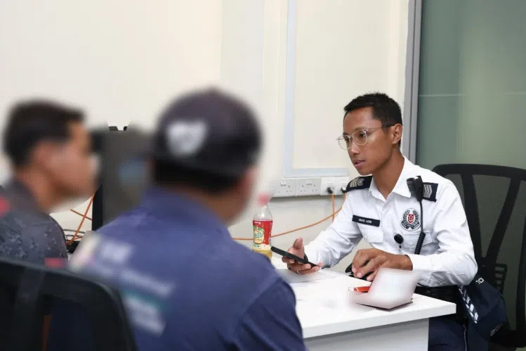 A Traffic Police officer speaking to two motorists about their outstanding fines.