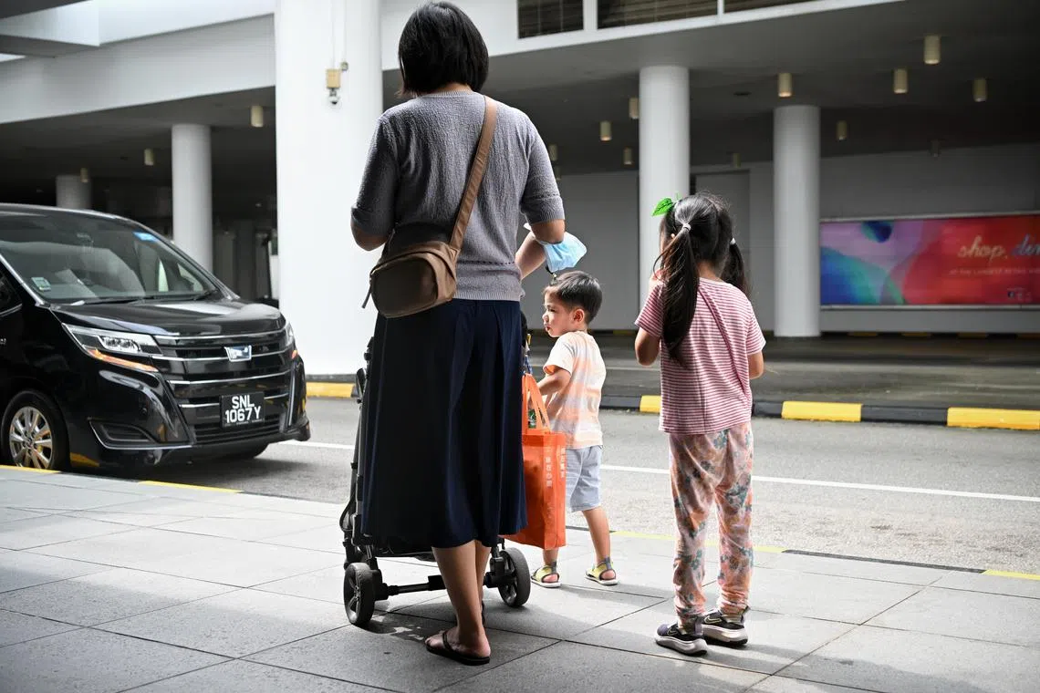 A mother and her children  waiting for their private hire car to arrive at the VivoCity taxi stand, 9 September 2023.