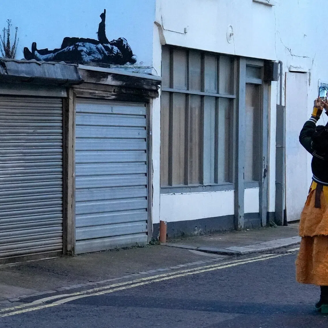 People taking photographs of a graffiti artwork by street artist Banksy, in Bayswater, west London, on Dec 22.