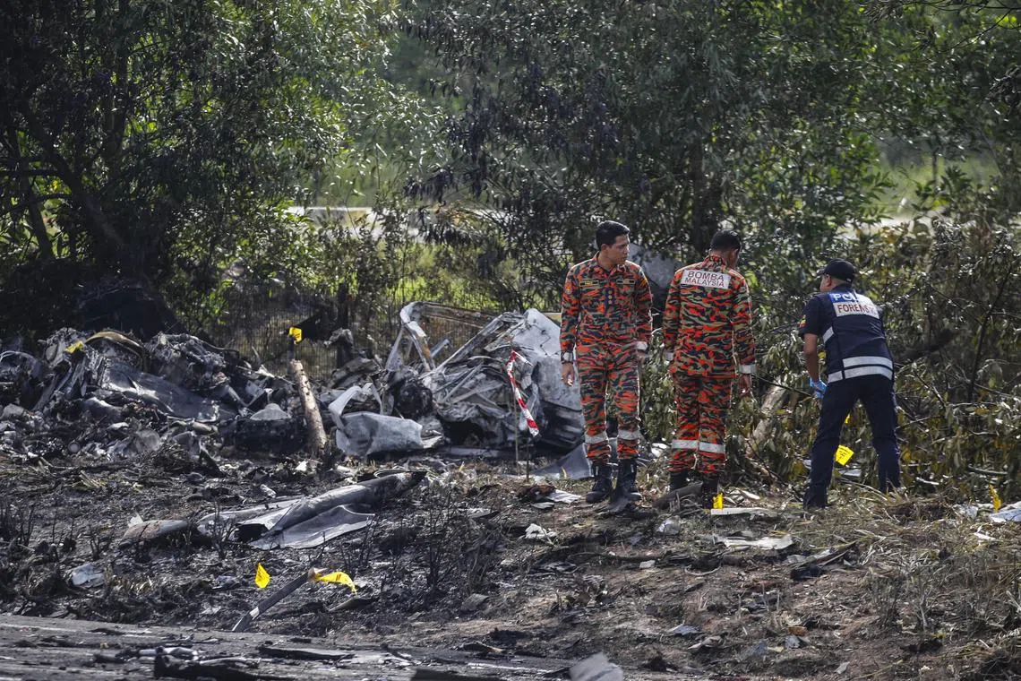 Royal Malaysia Police and Fire and Rescue Department officers at the scene of the light aircraft crash in Elmina on Thursday. 
