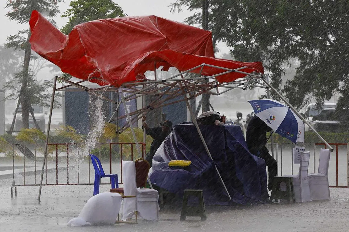 Security workers hold onto a tent in the heavy rain before the Southeast Asian Games closing ceremony at Morodok Techno National Stadium, Phnom Penh, Cambodia, May 17.