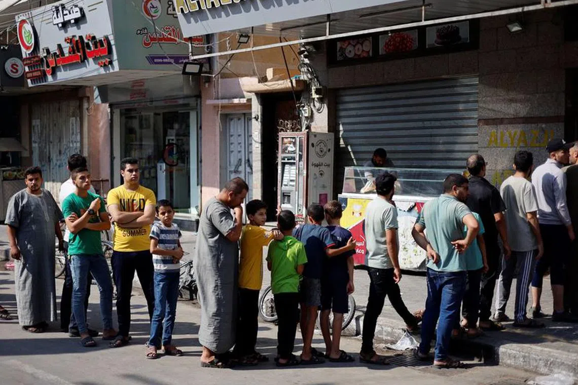 Palestinians wait to buy bread outside a bakery, amid the ongoing conflict between Israel and Palestinian Islamist group Hamas, in Khan Younis in the southern Gaza Strip, October 14, 2023. REUTERS/Mohammed Salem/File Photo