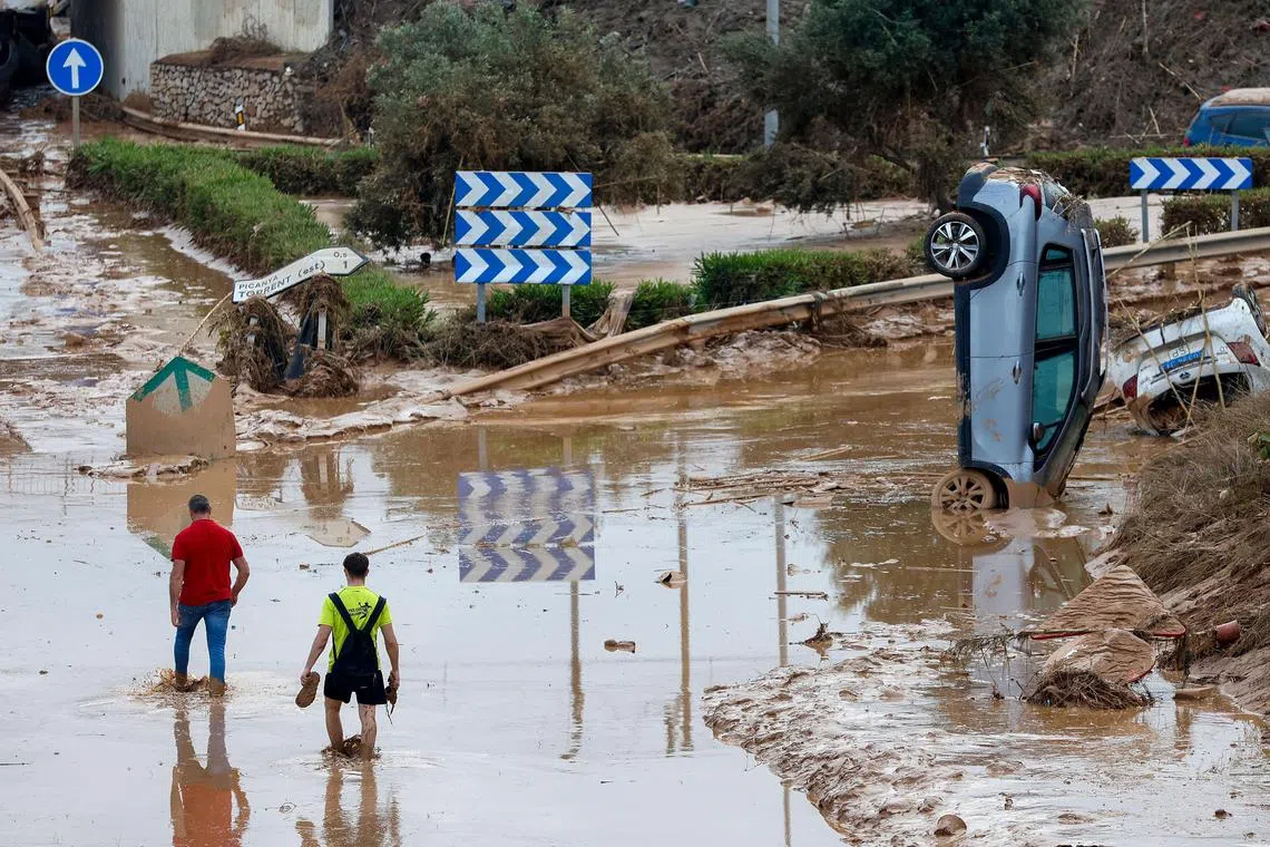 People walking along a mud-covered road in the flood-hit city of Picanya, in Spain's Valencia province, on Oct 31.