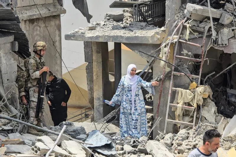 A woman making her way through the rubble on May 27 as a Lebanese soldier looks on at the site of a residential building hit by an Israeli strike near the southern town of Burj al-Shamali, on the outskirts of Tyre.