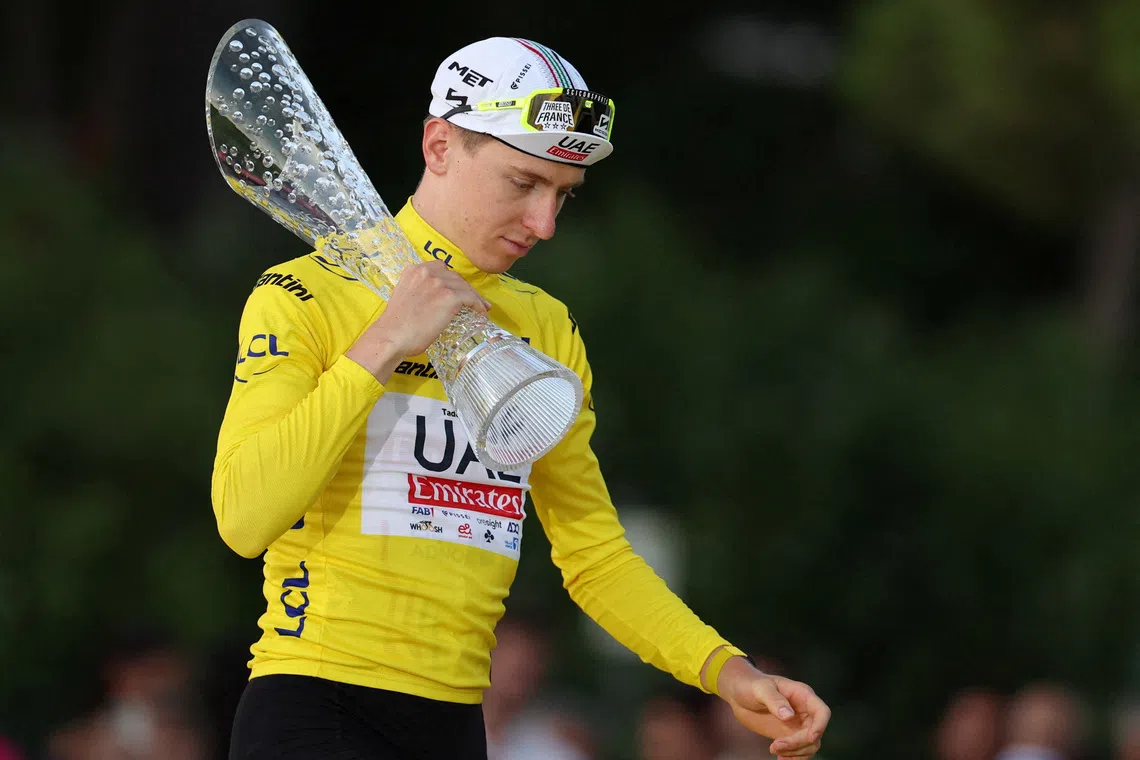 FILE PHOTO: Cycling - Tour de France - Stage 21 - Monaco to Nice - Monaco, France - July 21, 2024 UAE Team Emirates' Tadej Pogacar walks onto the podium wearing the yellow jersey with a trophy after winning the Tour de France REUTERS/Manon Cruz/File Photo
