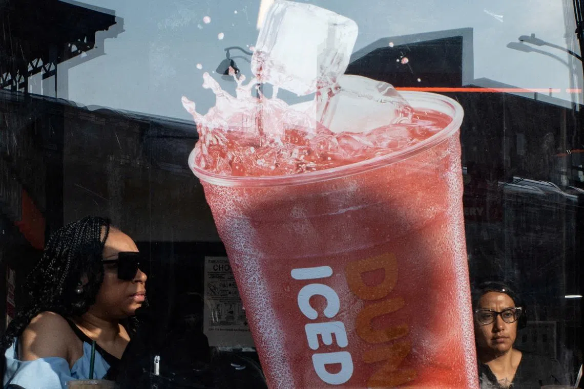 People walking past an advertisement for an iced drink amidst 35.6 degrees celsius temperatures in the Bronx, in New York City on June 23, 2025. 
