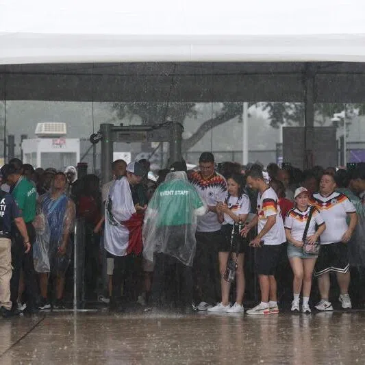 Fans seek shelter from the rain as they arrive before the FIFA World Cup 2026 Group E match between Germany and Curacao at Houston Stadium on June 14, 2026.