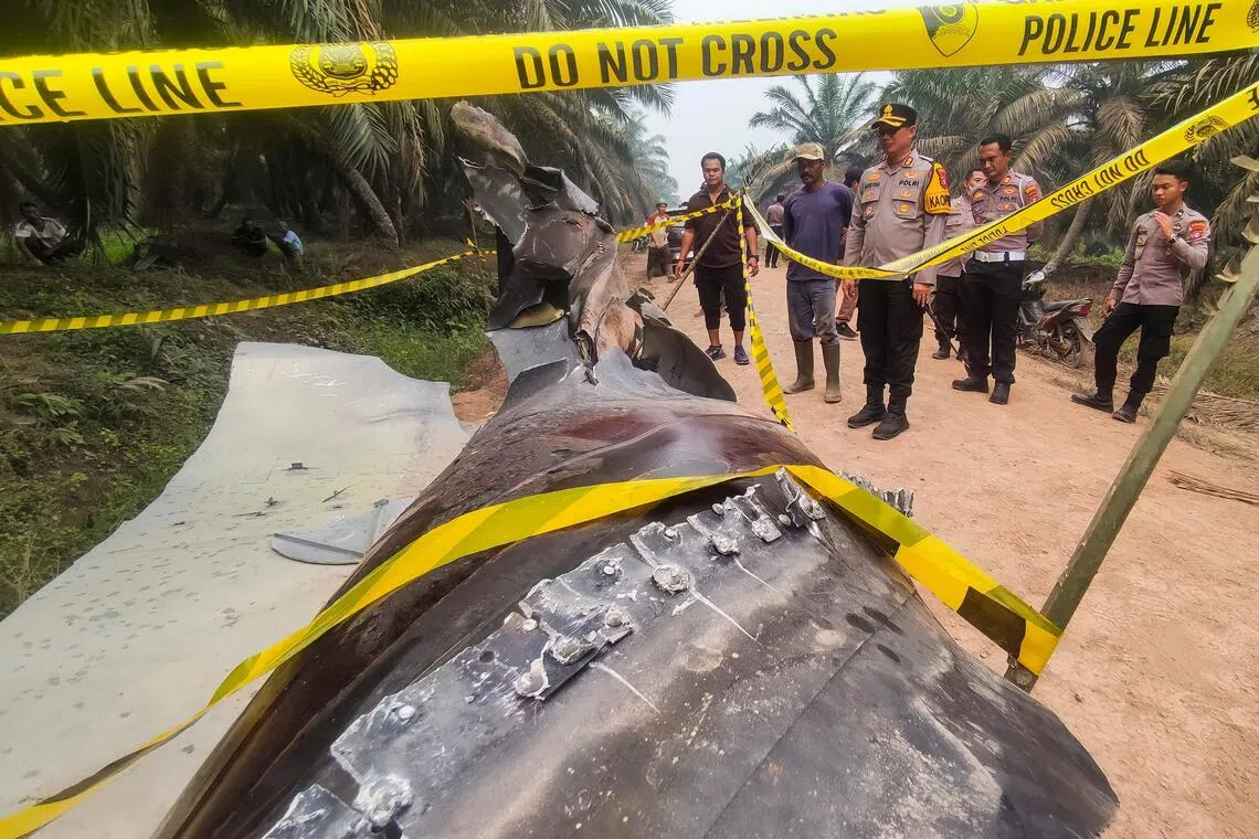 Indonesian police officers inspecting a large charred metallic fragment, suspected to be rocket debris, at an oil palm plantation in East Kotawaringin Regency, in Indonesia’s Central Kalimantan province on Oct 19.