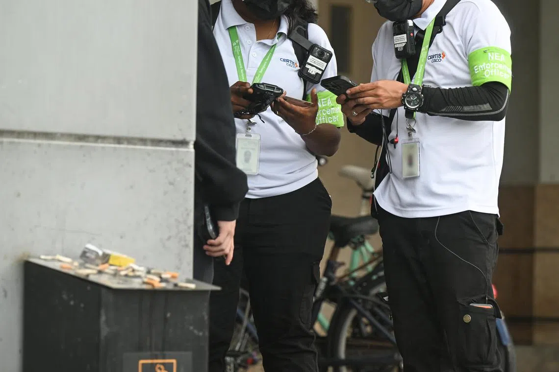 ST20240503_202499561572 wxnea06 Azmi Athni// Two National Environment Agency (NEA) enforcement officers catching a smoker who was smoking under a shelter along Causeway Point shopping mall on May 3. Embargo until May 6, 11am. ST PHOTO: AZMI ATHNI