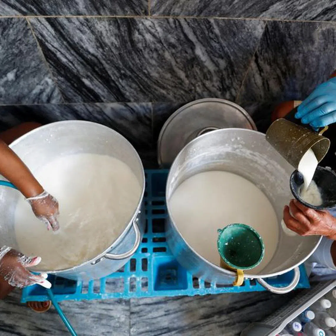 FILE PHOTO: Helpers fill bottles with milk to be distributed among people in need at a soup kitchen run by religious group Quisicuaba that is serving a growing number of Cubans struggling to make ends meet amid economic crisis, in Havana, Cuba January 15, 2024. REUTERS/Yander Zamora/File Photo