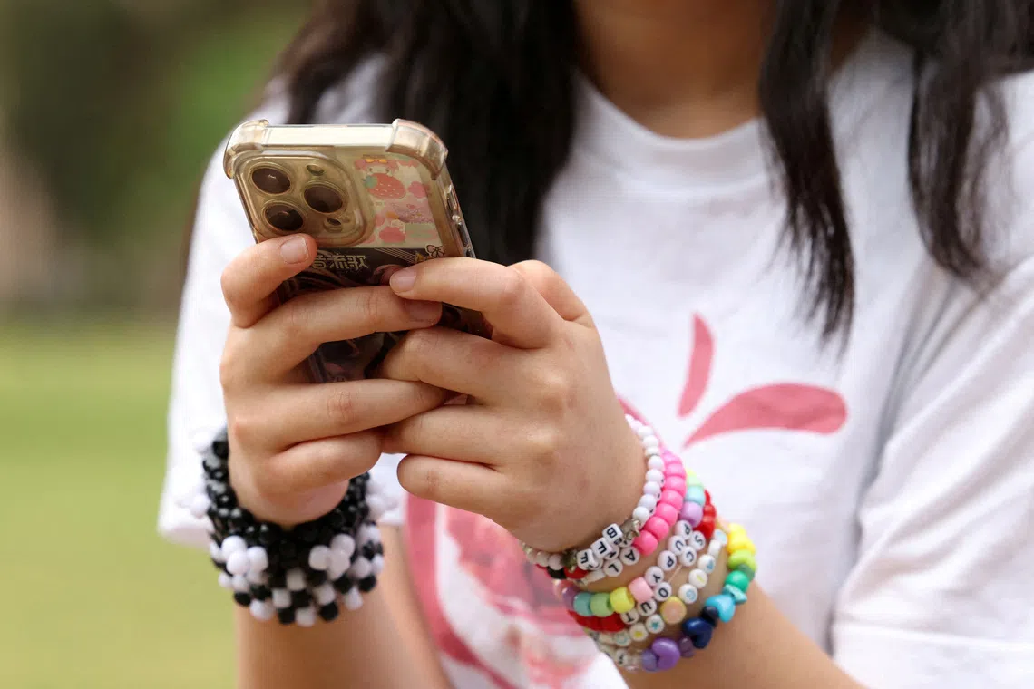 FILE PHOTO: A girl poses holding her phone after an interview discussing Australia's social media ban for users under 16, which is scheduled to take effect on December 10, in Sydney, Australia, November 22, 2025. REUTERS/Hollie Adams/File Photo