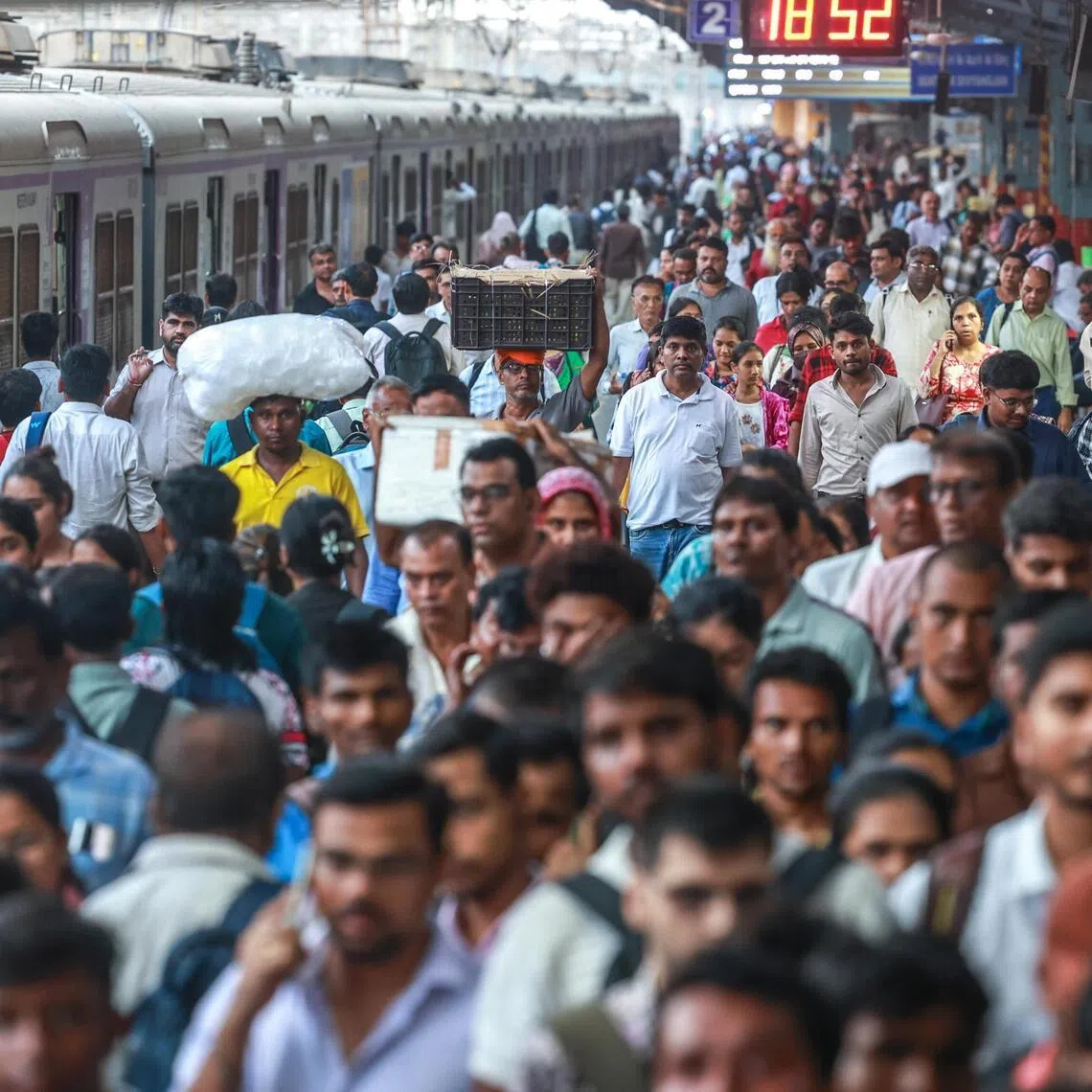 Commuters cross the platform after disembarking a local train at the railway station in Mumbai, India, on May 12, 2026.