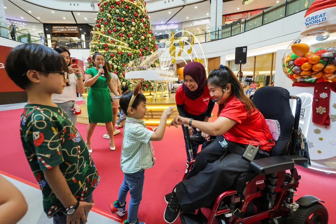 Singapore boccia athlete Jeralyn Tan (far right) interacting with a child as coach Yurnita Omar, (second from right) watches during the Great World Christmas Symphony with Cerebral Palsy Alliance Singapore event at Great Wall shopping mall atrium.