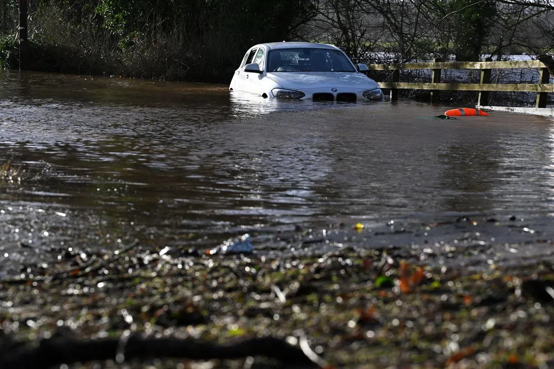 Floodwater water surrounds a flooded car abandoned by the side of a road, after the River Eden burst its banks during Storm Isha, near Warwick Bridge, north west England on January 22, 2024. Tens of thousands of people across the UK and Ireland were without power on Monday after Storm Isha lashed the countries with strong winds and heavy rain, disrupting travel networks. (Photo by Paul ELLIS / AFP)