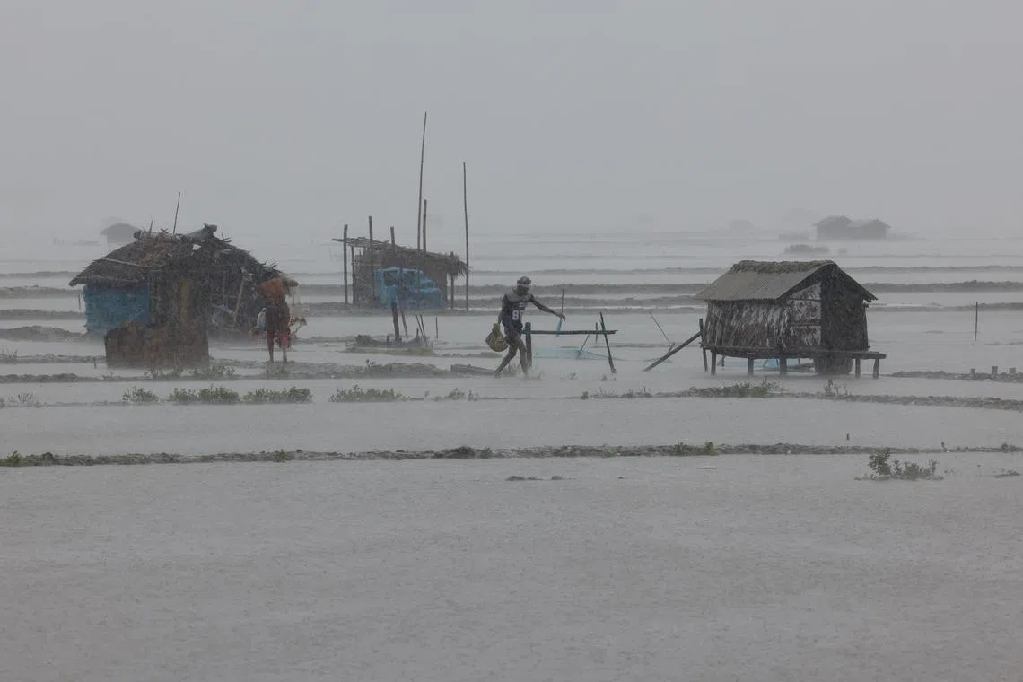 People walking along shrimp and crab farms that are flooded due to heavy rain as Cyclone Remal passes the country, in the Shyamnagar area of Satkhira, Bangladesh on  May 27, 2024. 