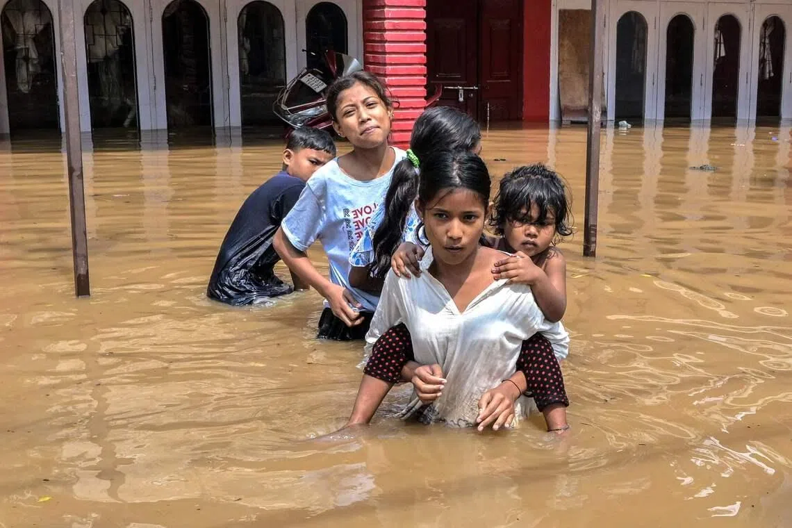 Children wading through floodwaters following heavy rainfall in Guwahati, India, on April 20, 2026. 