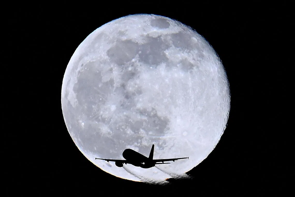 An aircraft passes in front of the moon as it flies over London, Britain, February 6, 2023. REUTERS/Toby Melville     TPX IMAGES OF THE DAY     
