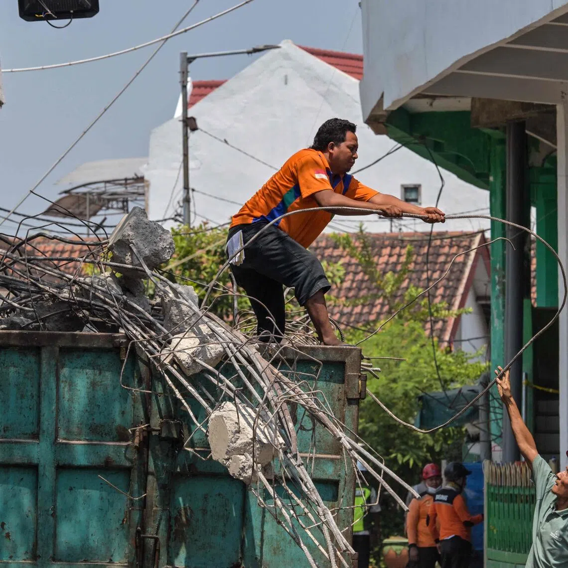 Rescue teams move debris from the collapsed building onto trucks as search and rescue operations continue at the site of a collapsed school in Sidoarjo, East Java province.
