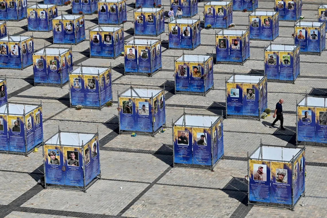 TOPSHOT - A man walks between stands displaying portraits of fallen Azov Brigade fighters, which have been set up at St Sophia Square in the center of Kyiv on September 15, 2026, amid the Russian invasion of Ukraine. (Photo by Sergei SUPINSKY / AFP)