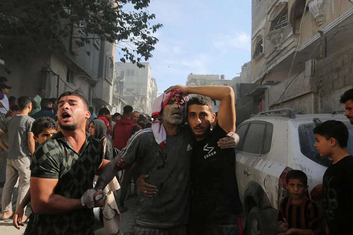 An injured Palestinian is assisted at the site of an Israeli strike on a house in Rafah in the southern Gaza Strip, Oct 30.