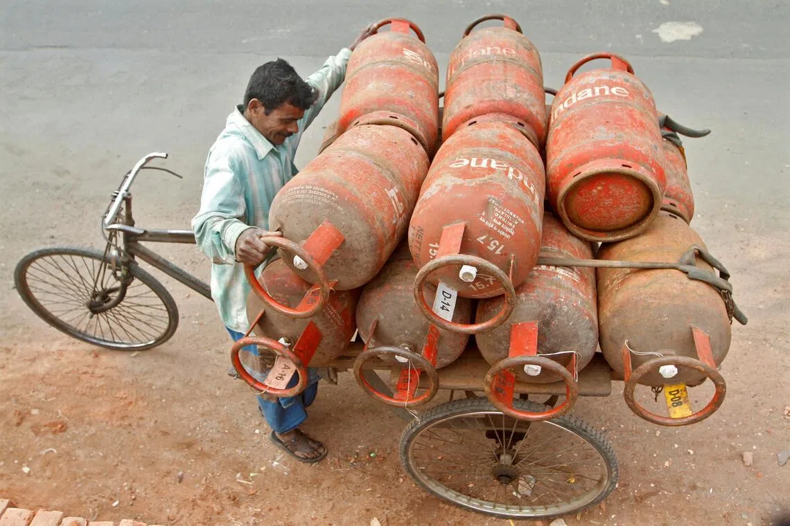 A worker loads liquefied petroleum gas cylinders onto his cycle-rickshaw in Kolkata, India.
