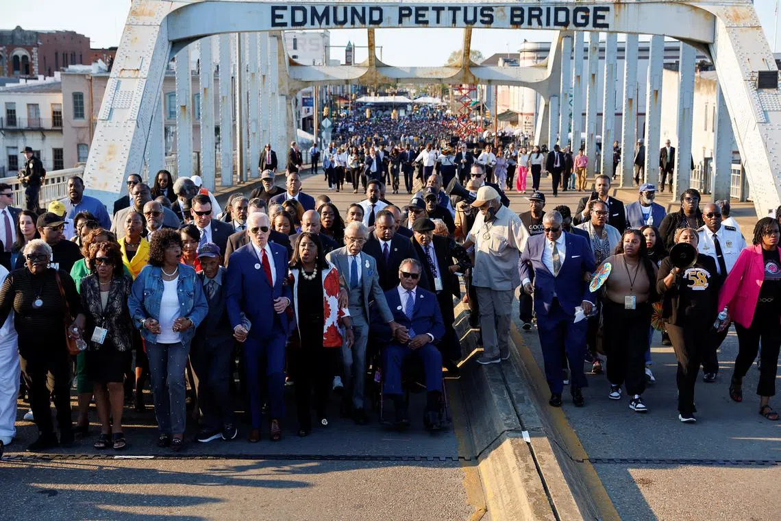 Mr Biden walks with civil rights activists across the Edmund Pettus Bridge during a commemoration of the 58th anniversary of Bloody Sunday in Selma, Alabama. 