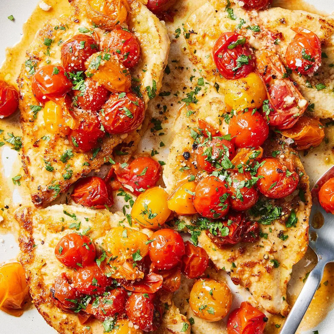 Lemon and garlic chicken with cherry tomatoes. Marinating the chicken breasts before pounding them flat makes them extra juicy and flavourful. Food styled by Simon Andrews. 