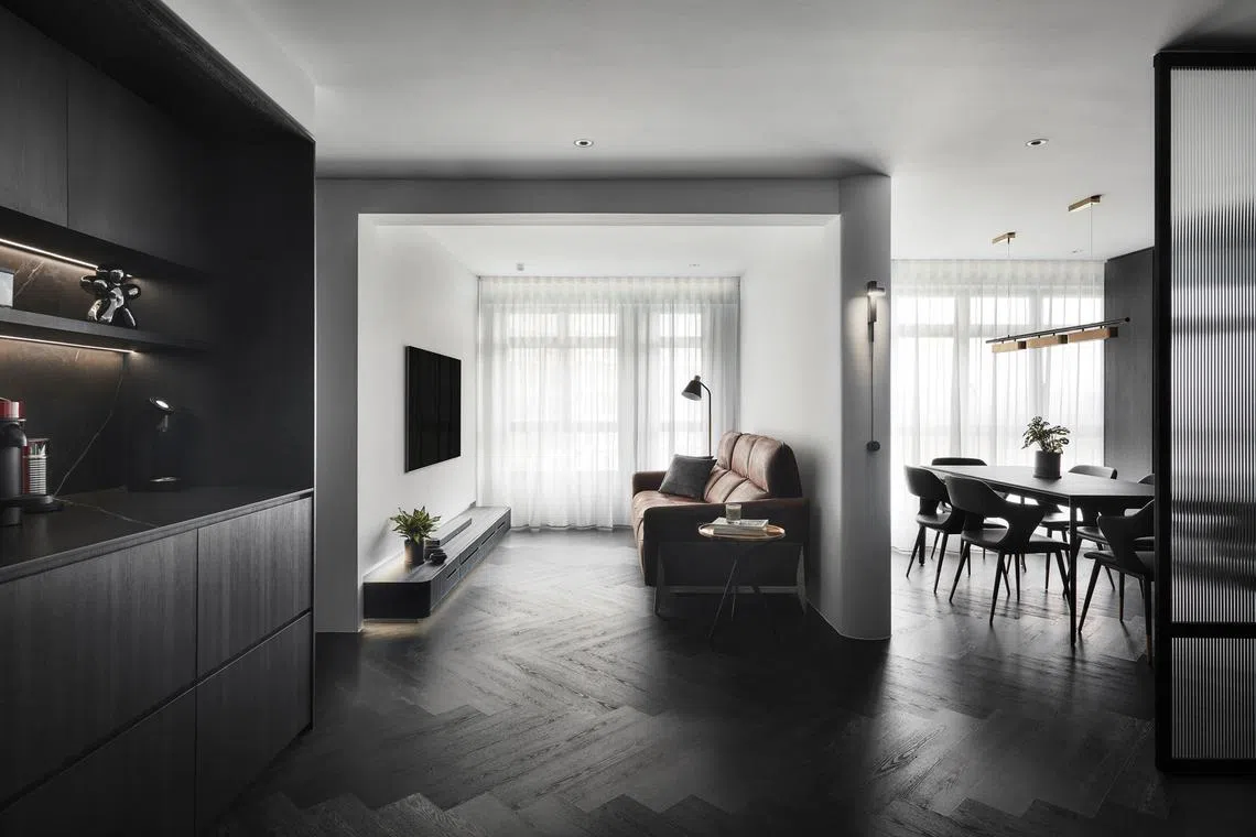 A palette of dark wood, dark grey and black permeates investment executive James Chua's HDB flat, with a white ceiling and some white walls for contrast. 