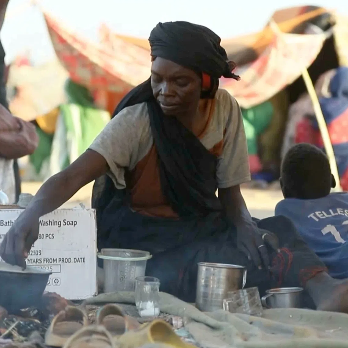 A displaced Sudanese woman makes tea while others gather and sit in makeshift tents after fleeing Al-Fashir city in Darfur, in Tawila, Sudan, October 29, 2025, in this still image taken from a Reuters' video. REUTERS/Mohamed Jamal