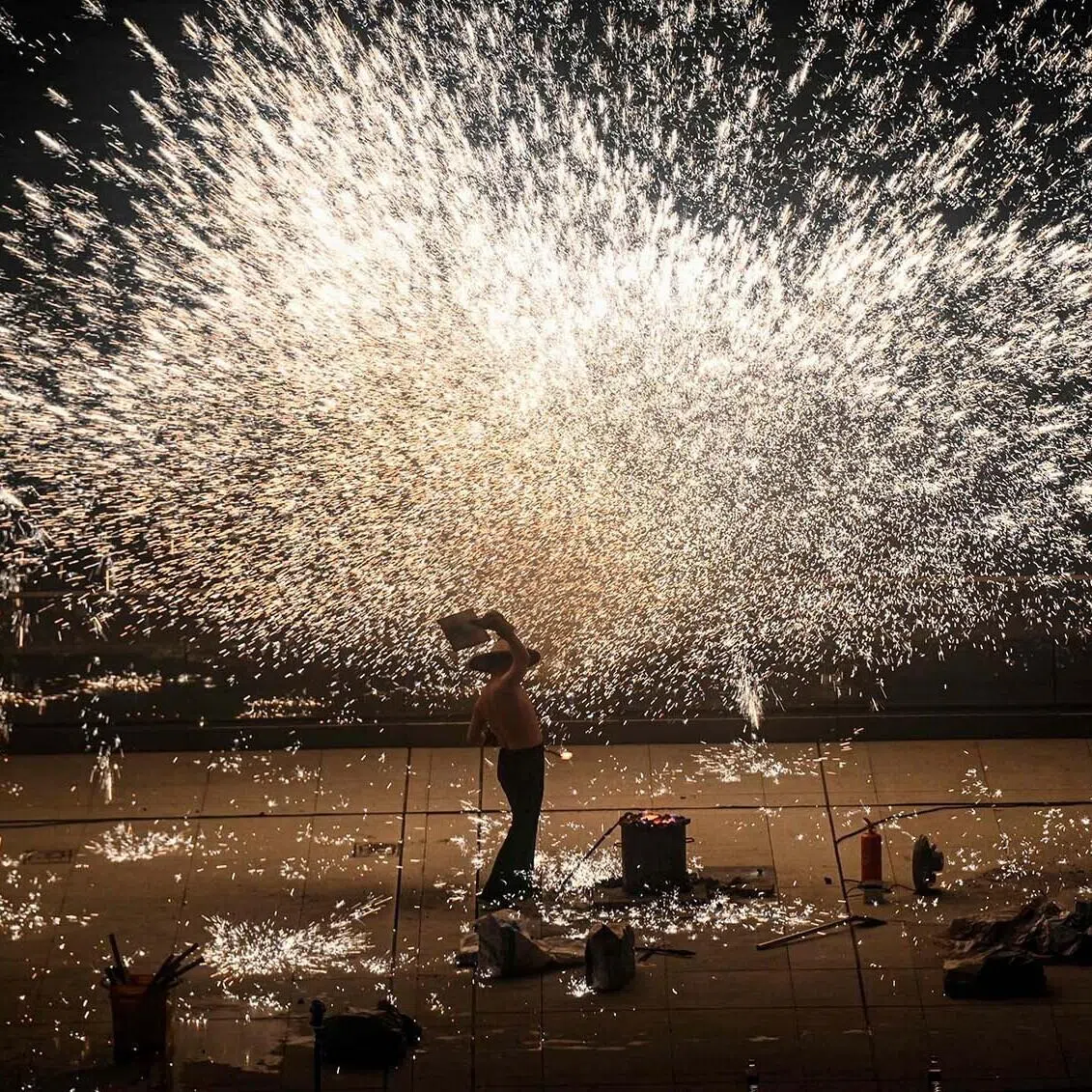 A performer throwing molten iron to create sparks during a performance on the Bund promenade along the Huangpu river, ahead of the upcoming Lunar New Year of the Horse in Shanghai on Feb 2, 2026. 