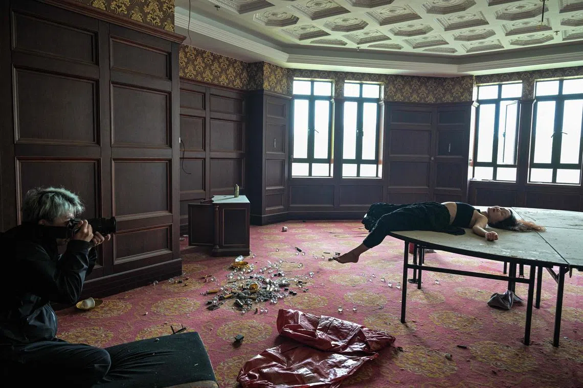 This photo taken on May 24 shows Xu Pengcheng (left) taking pictures of model Mao Yi as she poses on a table at a room inside an abandoned hotel in Shanghai. 