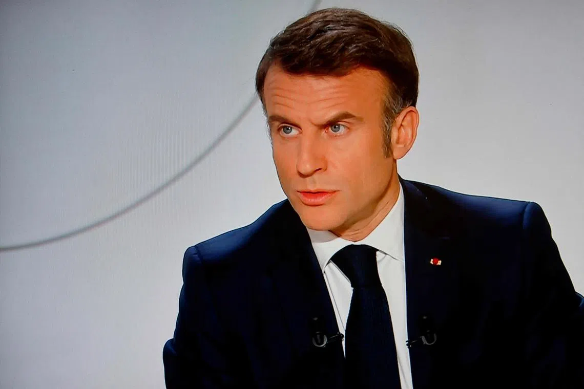 This photograph taken on March 14, 2024, shows a television screen broadcasting France's President Emmanuel Macron addressing a live interview on French TV channel France 2 at the Elysee Presidential Palace in Paris. Emmanuel Macron said on March 14, 2024, that France would "never" take the initiative to fight Russia, although he confirmed that no option should be ruled out in support of Ukraine. (Photo by Ludovic MARIN / AFP)
