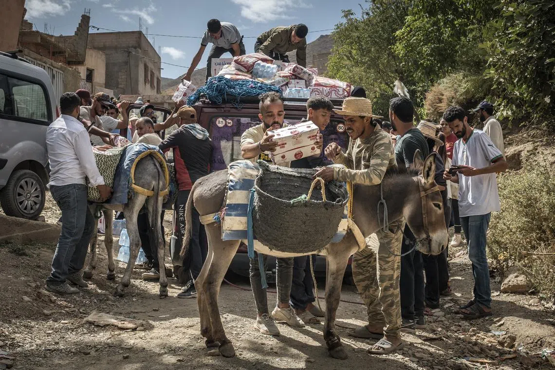 People loading aid to donkeys to transport to hard-to-reach houses in Douar Tnirt village in the Atlas Mountains, in the hard-hit Al Haouz province, Morocco, on Sept 10, 2023. 