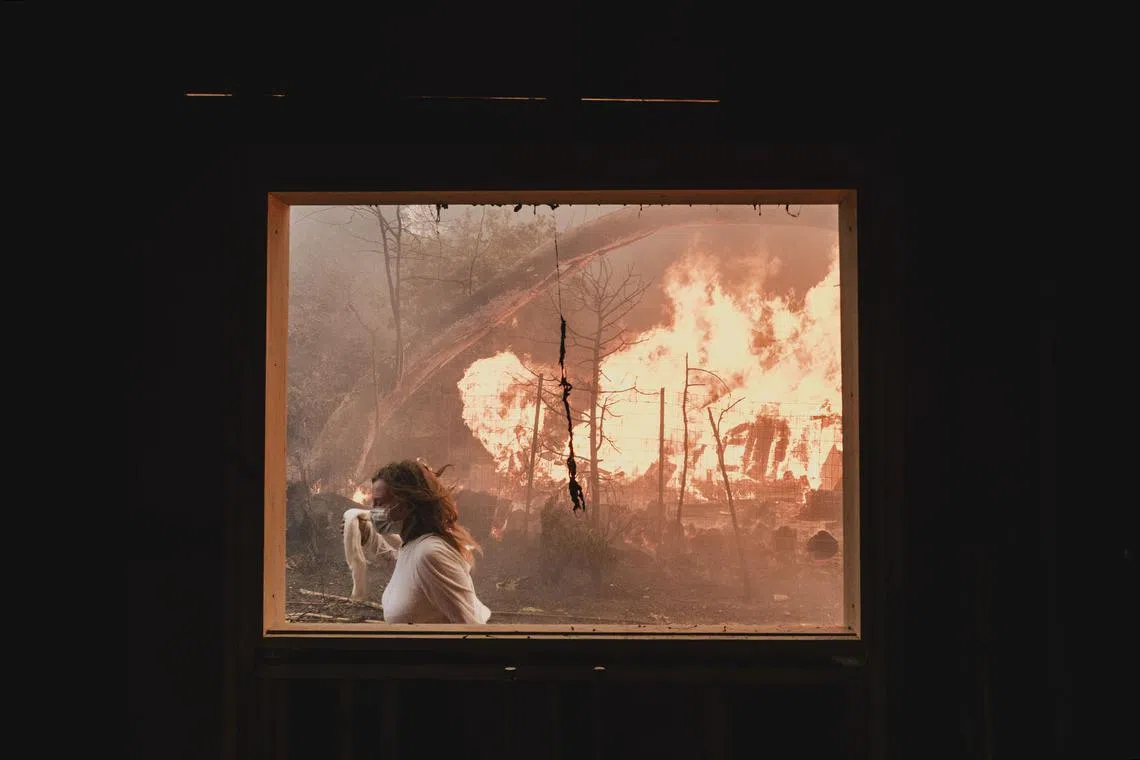 Nancy Chiamulon attempting to contain a fire encroaching on their property during the Palisades Fire in Los Angeles on Jan 8, 2025. 