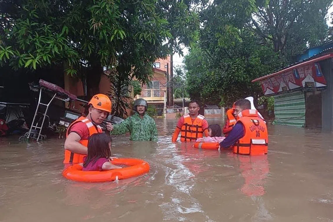 Children are evacuated from a flooded area by coast guard personnel in Lucena, Quezon Province, amid heavy rain brought by tropical storm Ewiniar on May 26. 