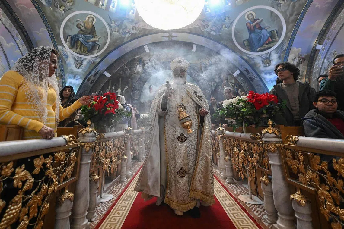 TOPSHOT - A priest leads Orthodox Christmas Eve celebrations at the Archangel Michael Coptic Orthodox Church in Cairo on January 6, 2025. (Photo by Ahmed HASAN / AFP)