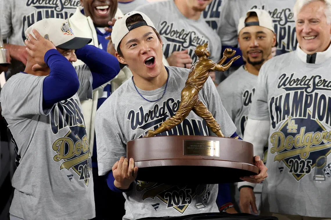 TORONTO, ONTARIO - NOVEMBER 02: Yoshinobu Yamamoto #18 of the Los Angeles Dodgers raises the Willie Mays World Series Most Valuable Player Award after defeating the Toronto Blue Jays 5-4 in game seven of the 2025 World Series at Rogers Center on November 02, 2025 in Toronto, Ontario.   Emilee Chinn/Getty Images/AFP (Photo by Emilee Chinn / GETTY IMAGES NORTH AMERICA / Getty Images via AFP)