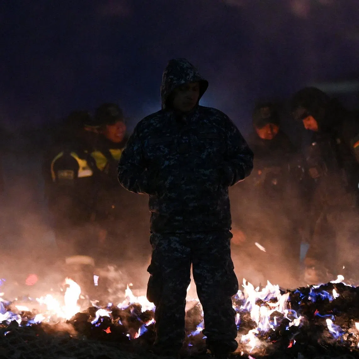 Members of the Bolivian military burn banknotes that fell from a Bolivian Air Force Hercules aircraft after it crashed on Friday evening onto a busy avenue amid inclement weather in the city of El Alto, Bolivia, February 28, 2026. REUTERS/Claudia Morales