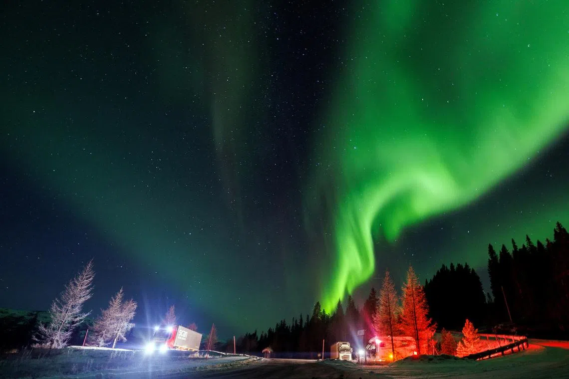 Northern Lights, also called Aurora Borealis, illuminate the night sky as cars park near a highway during autumn near Mo i Rana, Norway on November 15.