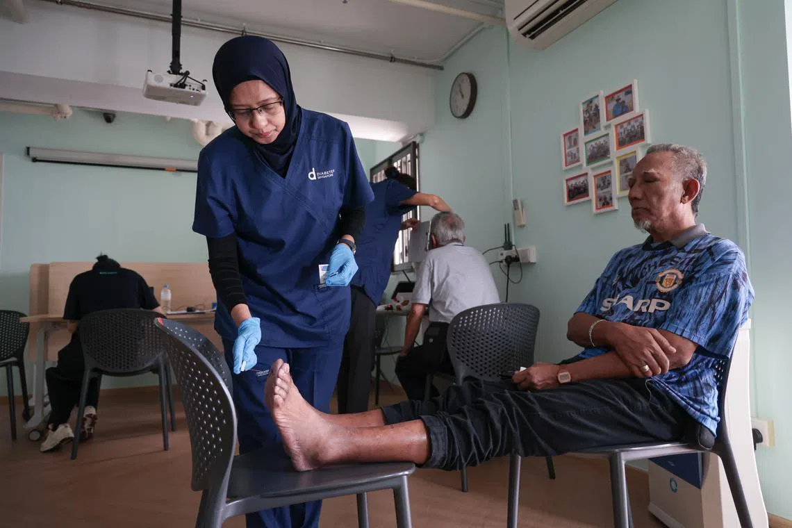 Retired security officer Mohamed Surip Jurimi (right) undergoing diabetic foot screening at the NTUC Health active ageing centre at Kampung Admiralty on July 17.