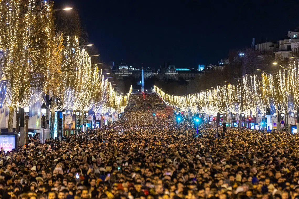 Revellers prepare to celebrate the new year 2023 and watching a light and fireworks show displayed on the Arc de Triomphe monument on the Champs-Elysees avenue in Paris, France, 31 Dec 2022.  