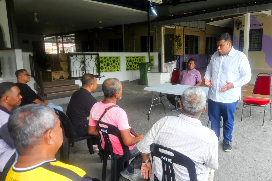 PKR state assemblyman Arafat Varisai Mahamad (standing) addresses villagers’ requests during a monthly town hall session held in a mosque compound in Kampung Ulu Chemor, Perak, on Aug 8.