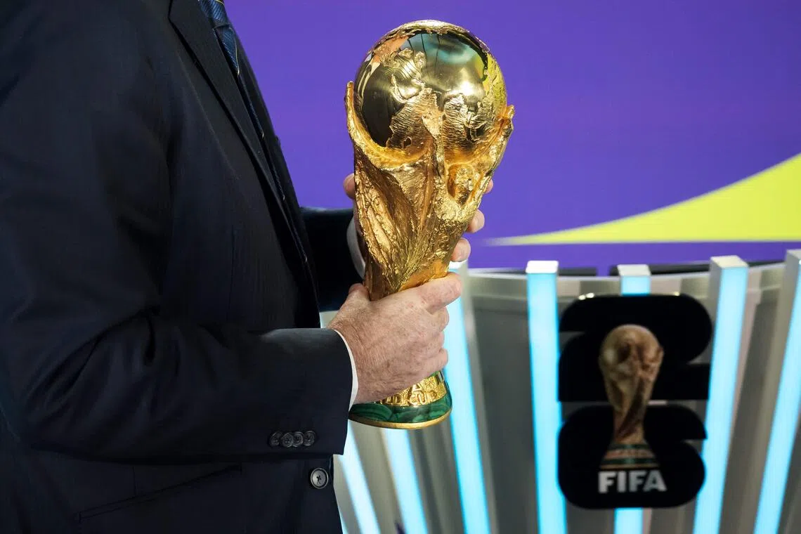 TOPSHOT - FIFA President Gianni Infantino holds the FIFA World Cup trophy following the 2026 FIFA World Cup European Play-Off draw at the FIFA's Home of Football in Zurich on November 20, 2025. (Photo by Fabrice COFFRINI / AFP)
