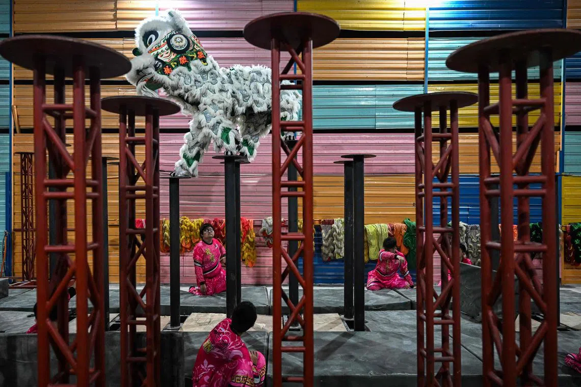 Members of a lion dance troupe practising on high poles ahead of celebrations for the Lunar New Year of the Rabbit in Kuala Lumpur. 