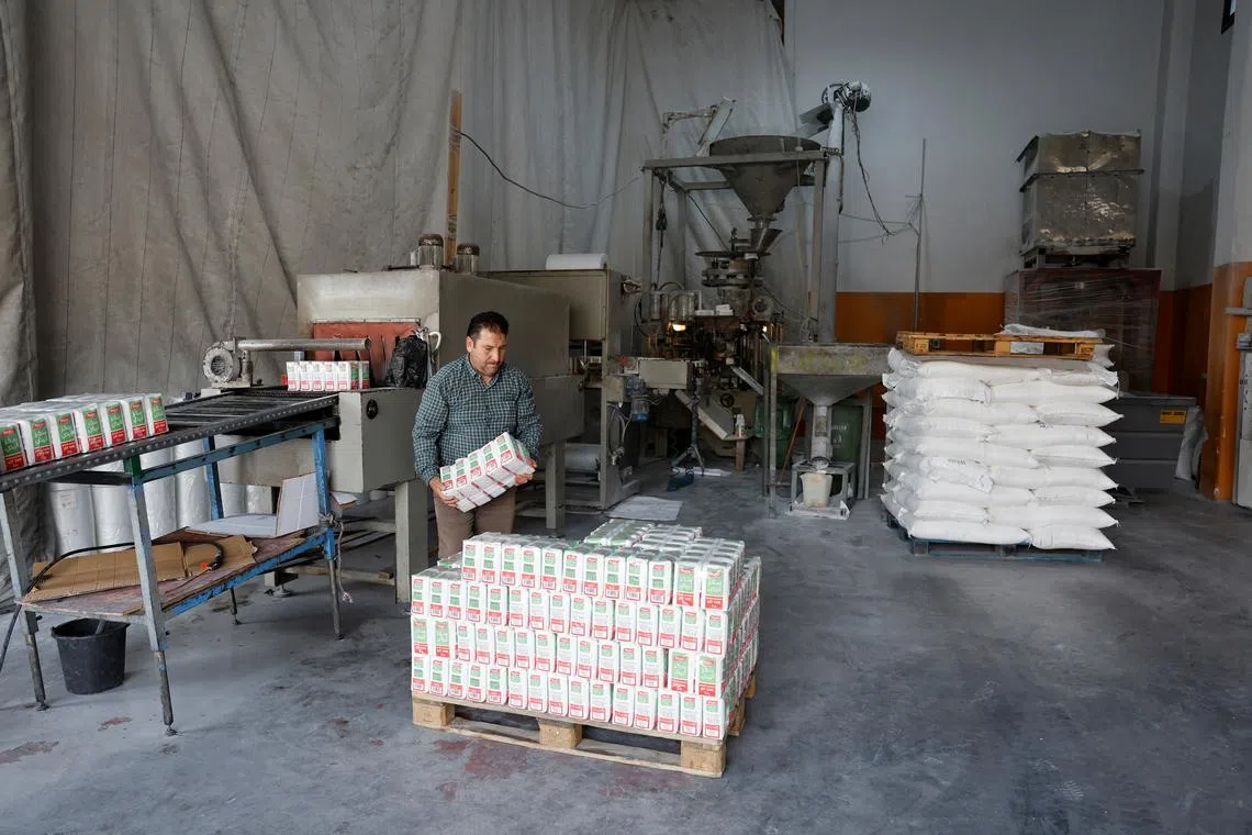 FILE PHOTO: A Palestinian worker loads bags of sugar in a warehouse, amid the ongoing conflict in Gaza between Israel and the Palestinian Islamist group Hamas, in Hebron, in the Israeli-occupied West Bank May 28, 2024. REUTERS/Mussa Qawasma/File Photo