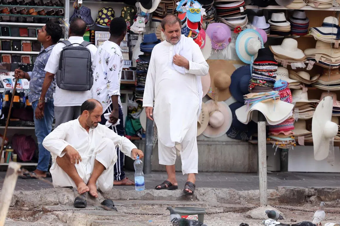 Workers rest along a pavement on a hot summer day in Dubai on July 12, 2023. The heat was felt in the United Arab Emirates, along with other Arab Gulf states, where warming trends brought on by climate change threaten to make entire cities unlivable by the end of the century, according to experts. (Photo by Karim SAHIB / AFP)
