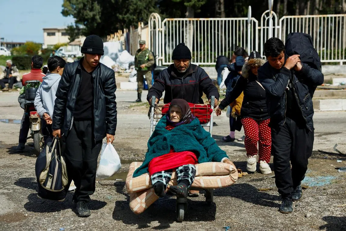 A man pushes an elderly woman on an airport luggage trolley at Hmeimim Air Base, in Latakia, western Syria, March 20, 2025. Thousands of Alawite families sought refuge there after deadly attacks by pro-government forces targeting their villages. A Reuters investigation found the violence left nearly 1,500 people dead.  REUTERS/Stringer    To match Special Report SYRIA-SECURITY/COASTAL-KILLINGS