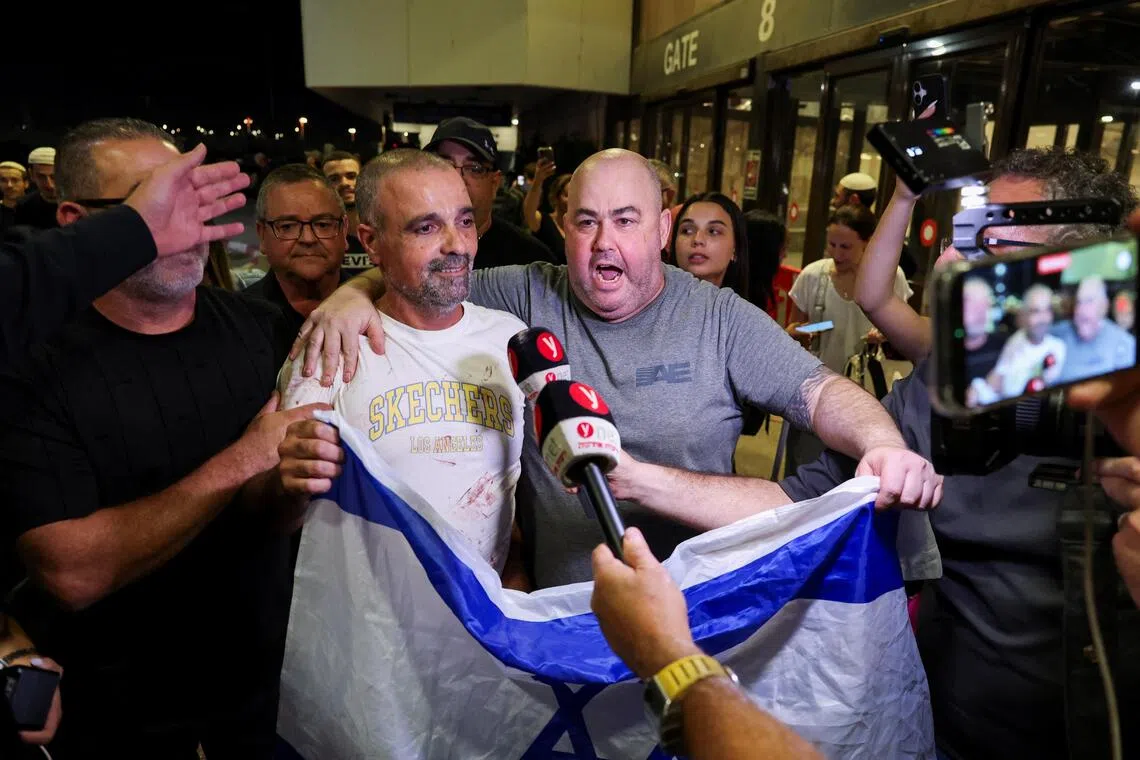 Yaniv Hayun (left) - one of the men who helped incapacitate the attacker on a flydubai aircraft from the UAE to Israel - holding an Israeli flag as he returns to Israel on Sept 30.