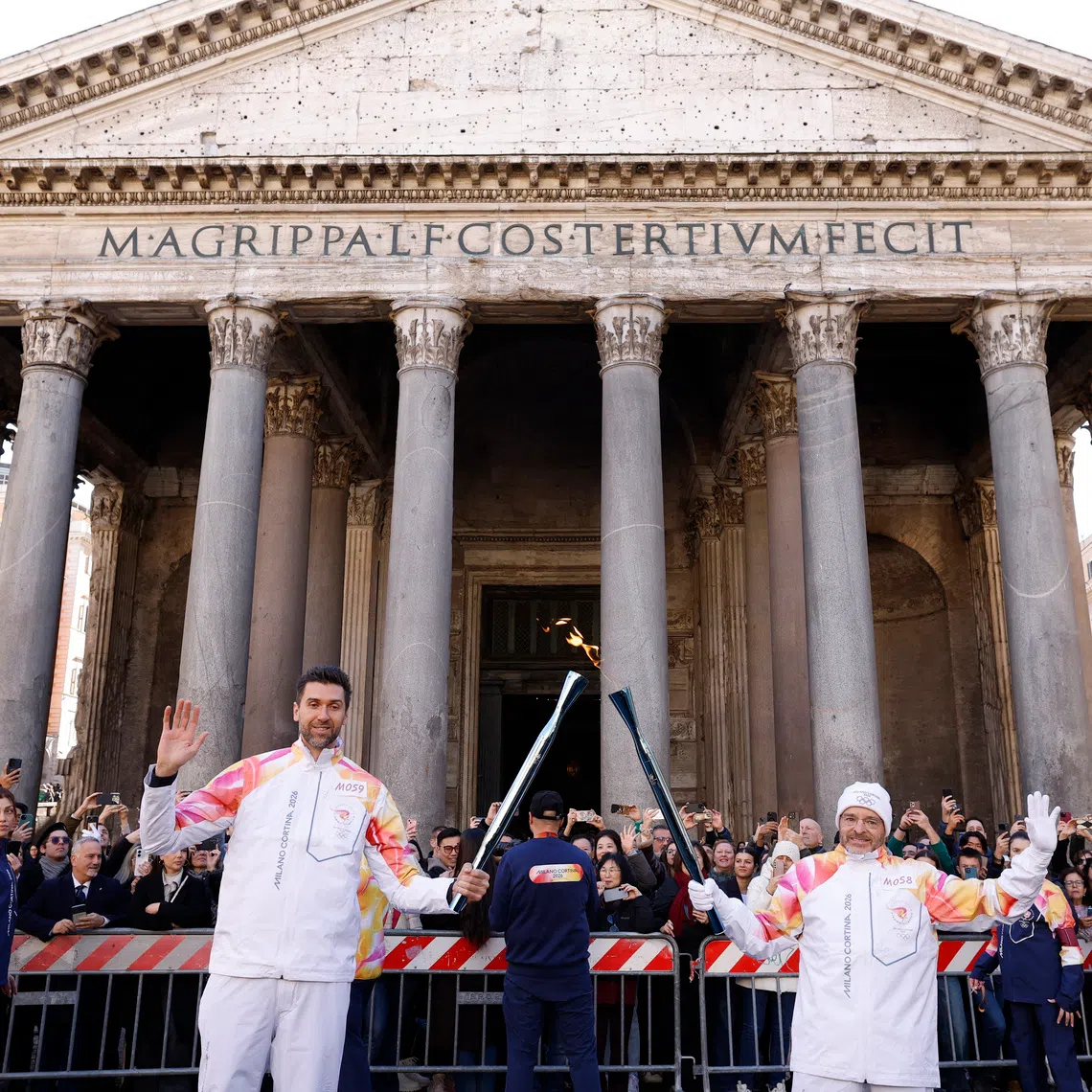Olympics - 2026 Milano-Cortina Winter Olympics - 2026 Milano-Cortina Winter Olympics Torch Relay - Rome, Italy - December 6, 2025  Former basketball player Italy's Andrea Bargnani is passed the Olympics flame during the relay as the Pantheon is seen in the background REUTERS/Remo Casilli