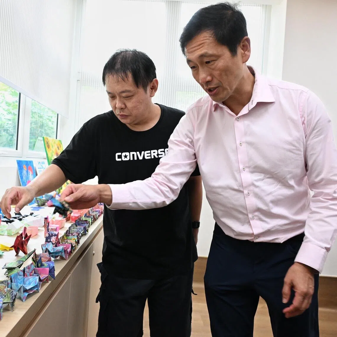 Health Minister Ong Ye Kung (right) picking up an origami made by a Compass Home client at the official opening of Vanguard Healthcare’s Hougang facility on Oct 5.